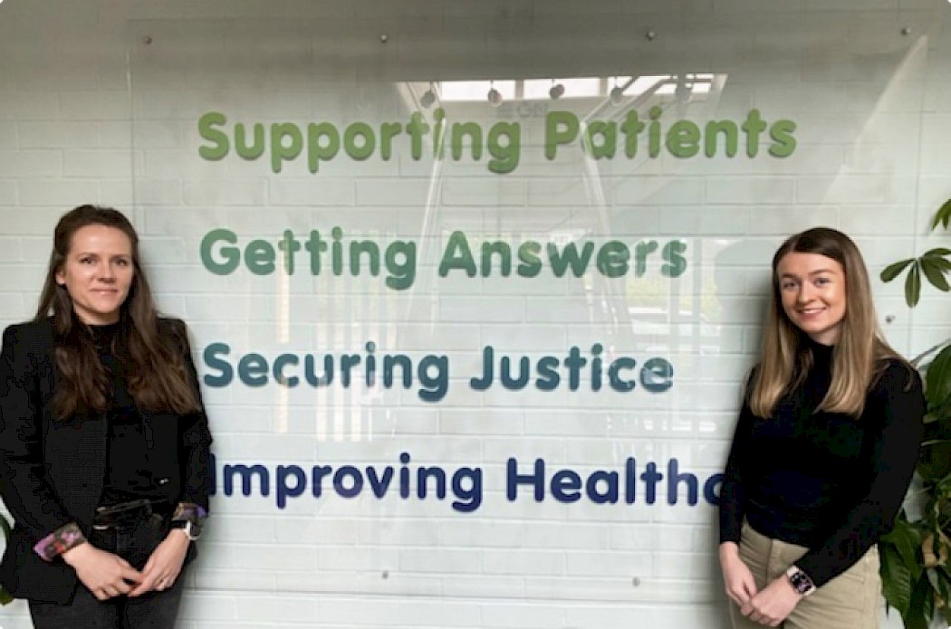 Two Medical Solicitors Smiling and Stood Infront of a Support Quote