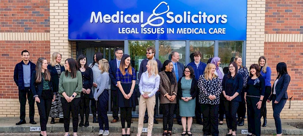 Group of medical solicitors standing outside their office smiling and chatting