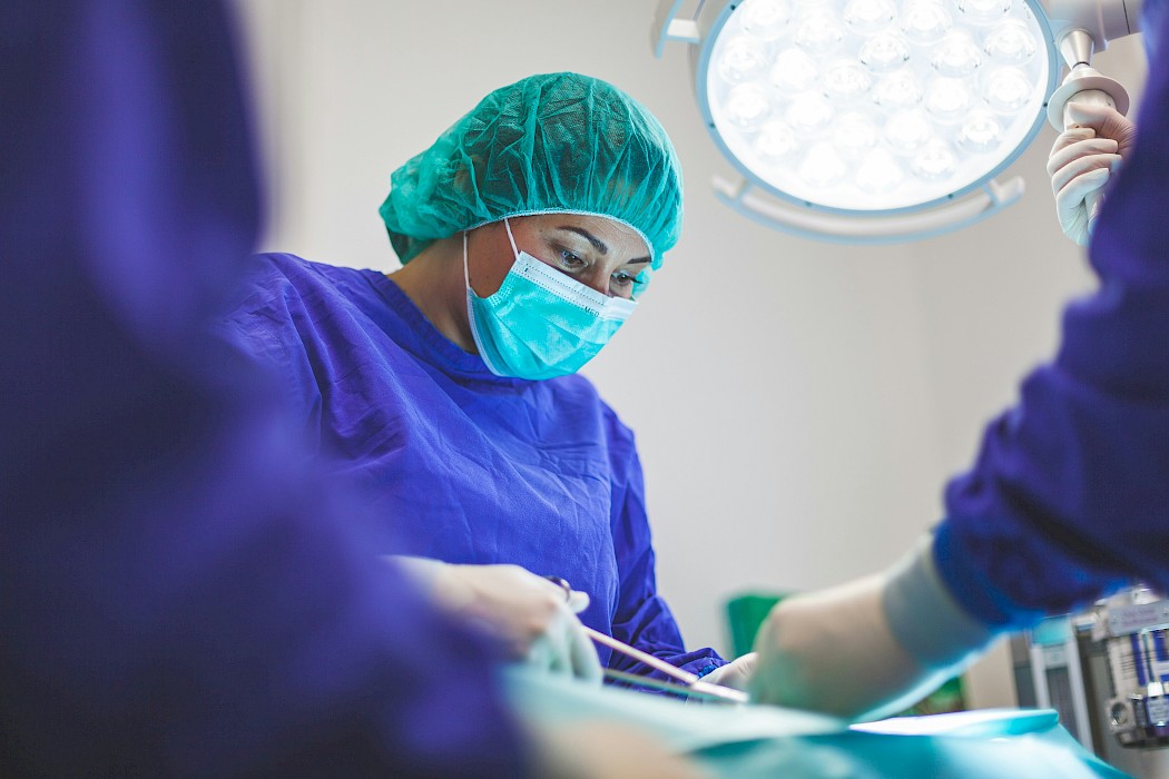 Female surgeon dressed in PPE performing surgery.