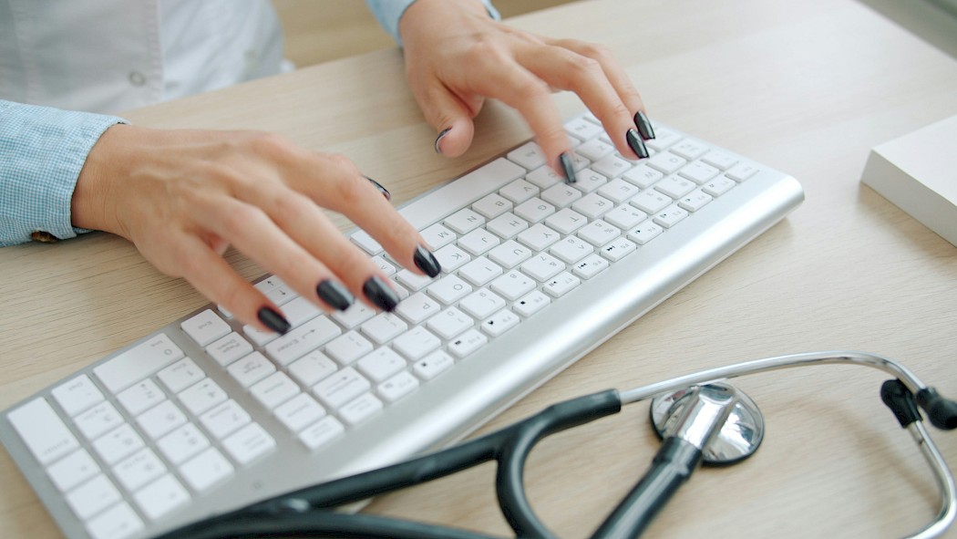 Female doctor typing with a telescope at the side.
