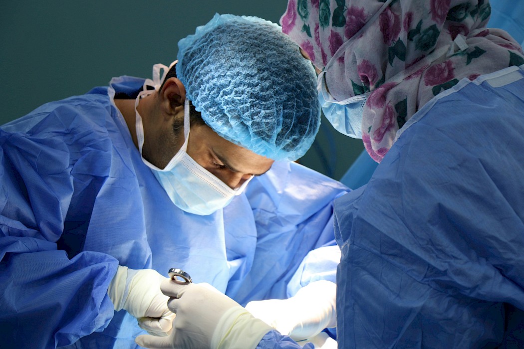 Two surgeons performing surgery wearing PPE.
